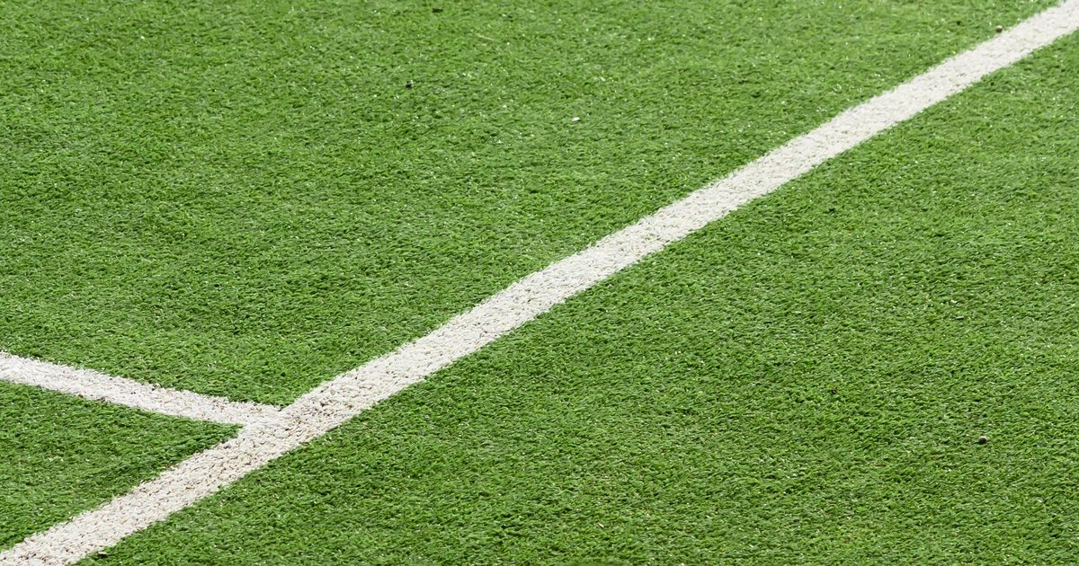 Close-up of green synthetic turf blades with white boundary lines